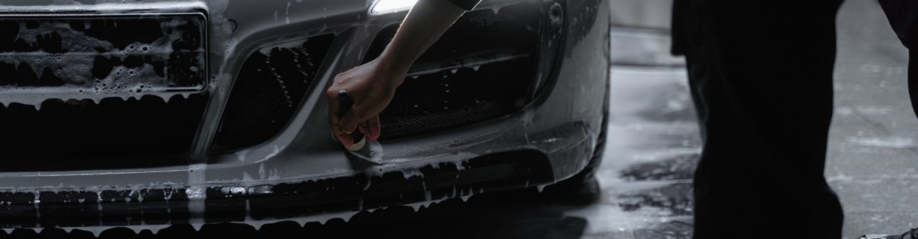 Coche siendo lavado profesionalmente en exterior, con espuma y equipo especializado