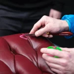 Técnico aplicando compuesto de relleno en superficie de cuero para reparar grietas y daños